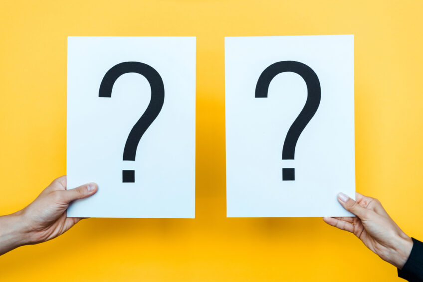 woman and a man holding each holding up a piece of paper with a question mark on each